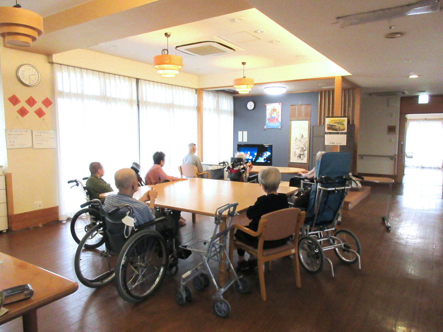 介護施設の共用部で、車椅子の入居者が集まるレクリエーションスペース